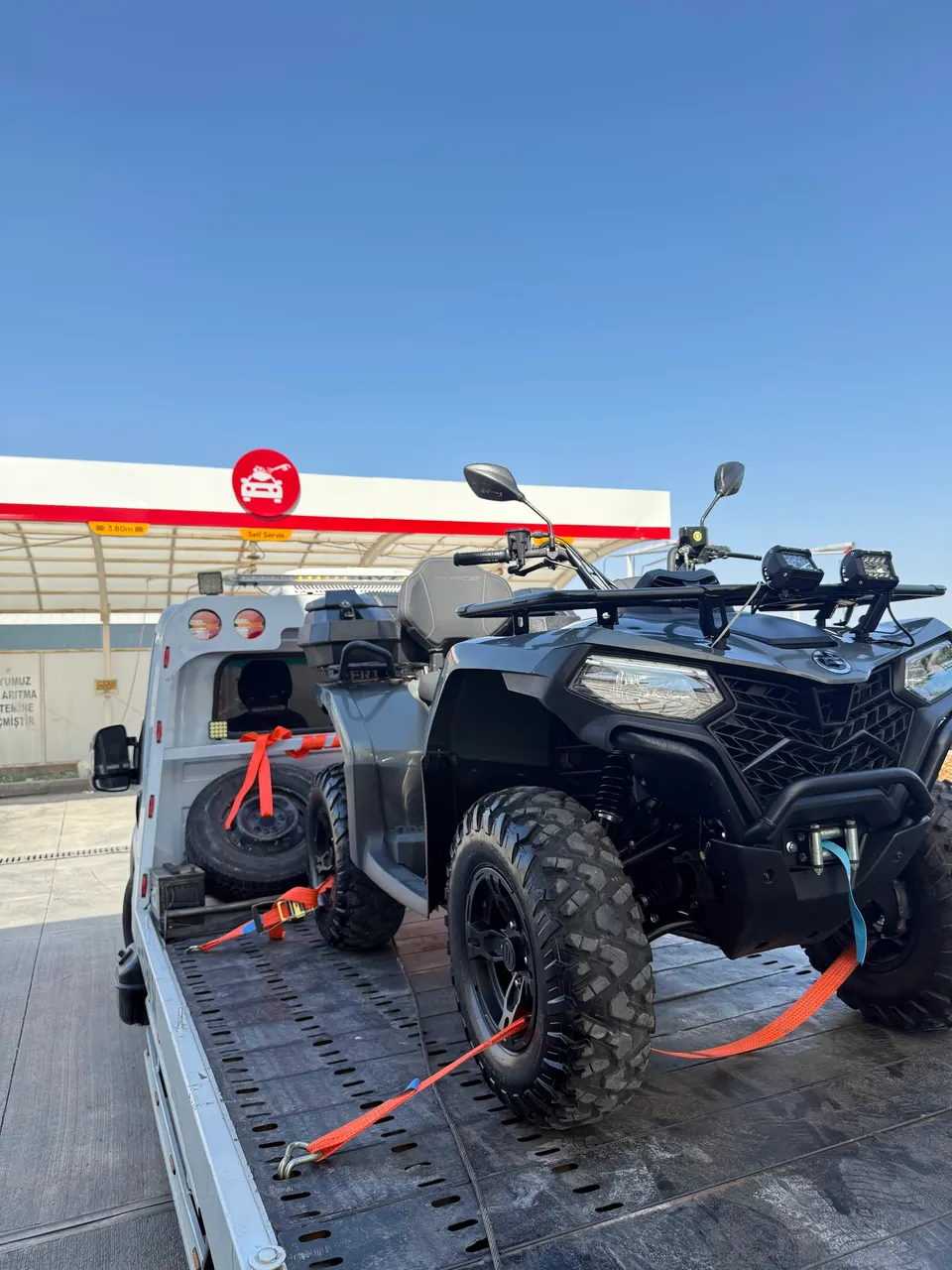 Çekici kasasında kayışlarla sabitlenmiş siyah ATV