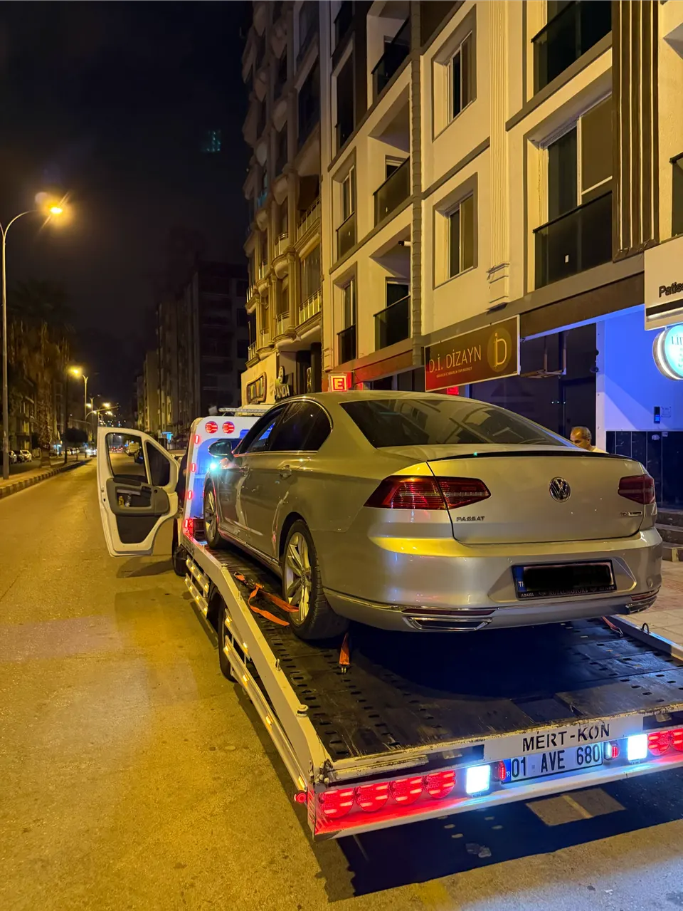 Gece şehir içinde çekici kasasına yüklenmiş gri Volkswagen Passat